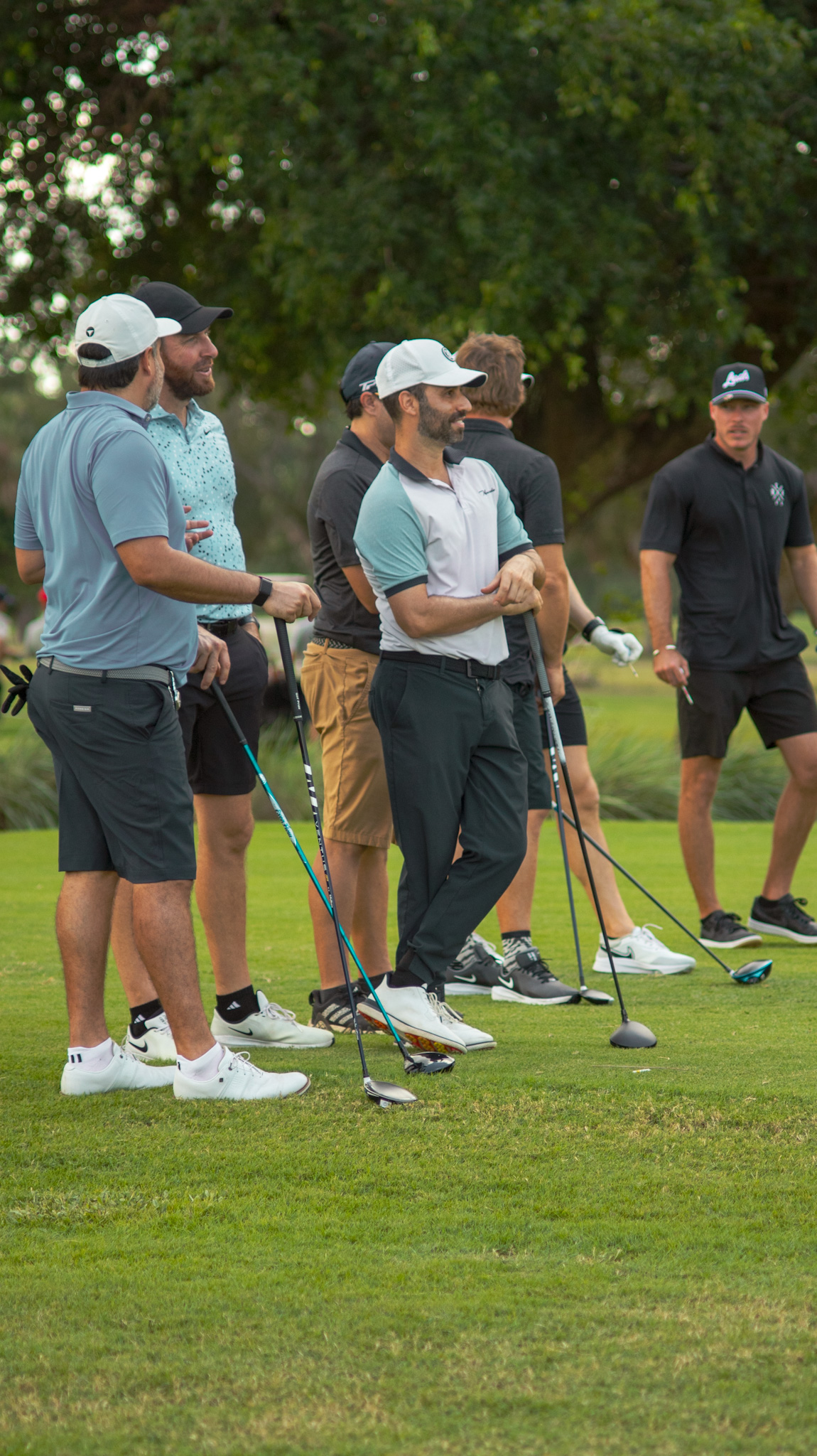 Players sharing a laugh under a shade tree between holes
